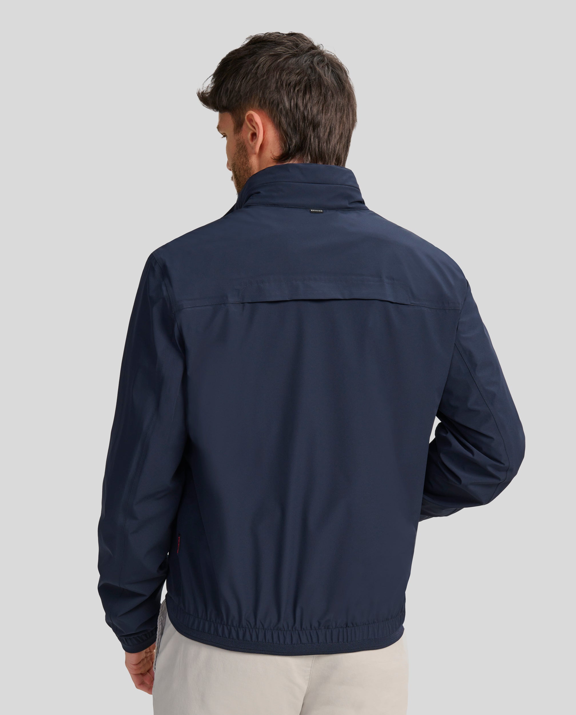 Buccino | DAMASO | MARINO | Foto de Espalda | Cazadora tejido CROMDALTEX repelente al agua y al viento con capucha oculta, con punto elástico fino en cintura y puños. Forrada rejilla. Dos bolsillos laterales de fácil acceso y un bolsillo en el interior con cremalleras waterproof. Cierre frontal con cremallera waterproof personalizada.