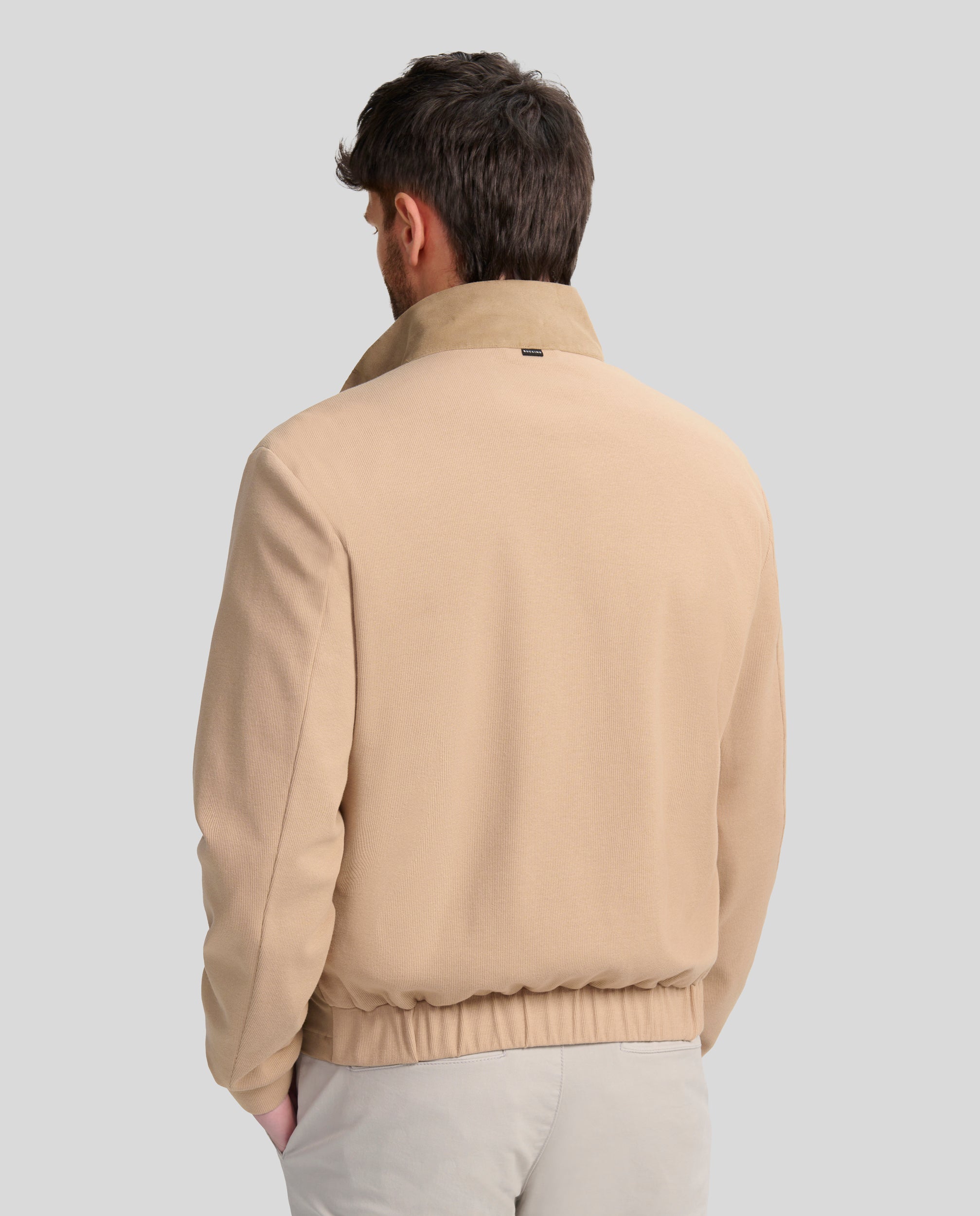 Buccino | GERARD | TOSTADO | Foto de espalda | Cazadora en tejido AMARA en el delantero combinada con punto en mangas y espalda. Forrada liso al tono. Dos bolsillos laterales de fácil acceso con cremallera y un bolsillo en el interior. Cierre frontal con cremallera vista personalizada.